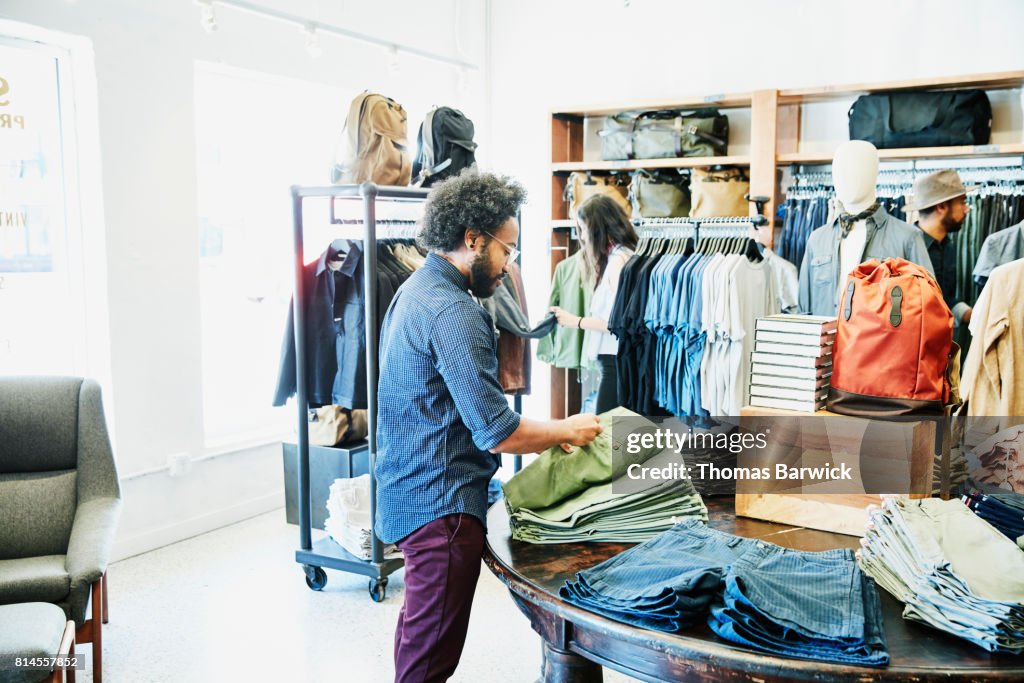 Man looking at shorts while shopping in mens clothing boutique