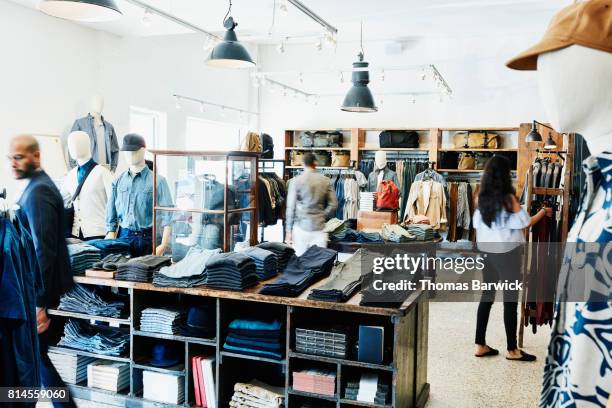 shoppers looking at items in mens clothing boutique - clothing store stockfoto's en -beelden