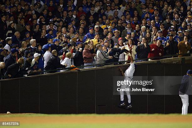 Baseball: NLCS Playoffs, Chicago Cubs Moises Alou in action, attempting foul ball catch foul vs Florida Marlins, Cubs fan Steve Bartman reaching and...