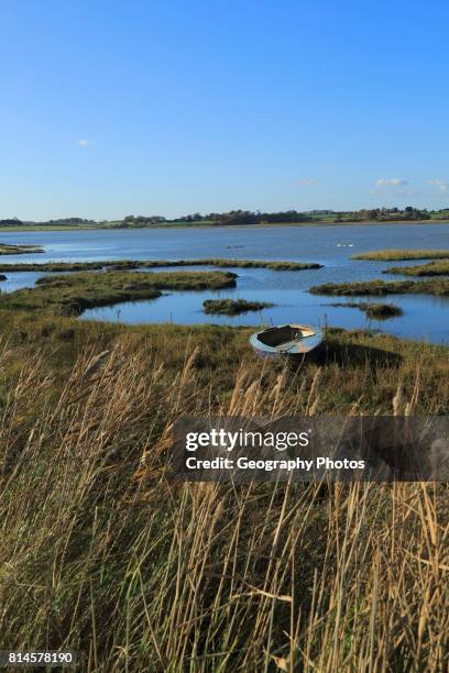 Winter landscape with small beached boat, River Deben, Ramsholt, Suffolk, England, UK.