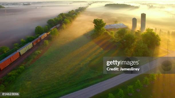 鉄道は夜明けに霧の農村風景をロールバックします。 - 貨物列車 ストックフォトと画像