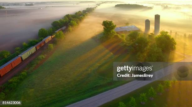 train rolls through foggy rural landscape at dawn. - comboio de mercadorias imagens e fotografias de stock
