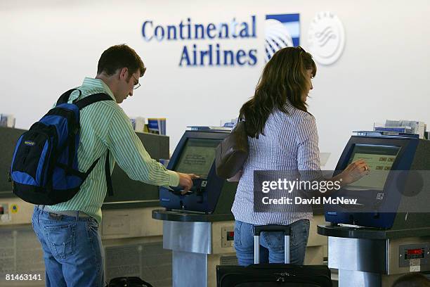 Passengers serve themselves at the electronic ticketing machines at the Continental Airlines ticket counter at Los Angeles International Airport on...