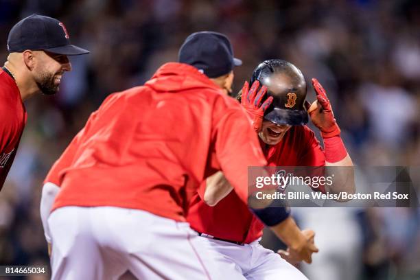 Andrew Benintendi of the Boston Red Sox is mobbed by teammates after being walked to drive in the game winning run during the ninth inning of a game...