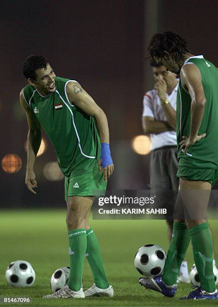 Iraqi player Yunes Mahmud smiles at teammate Nashat Akram as they take turns to shoot the ball during a training session at al-Ahli club in Dubai...