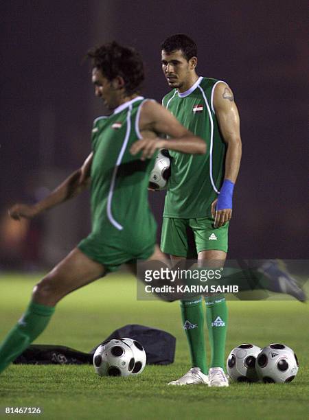 Iraqi player Yunes Mahmud looks at teammate Nashat Akram as he shoots the ball during a training session at al-Ahli club in Dubai late June 5, 2008...