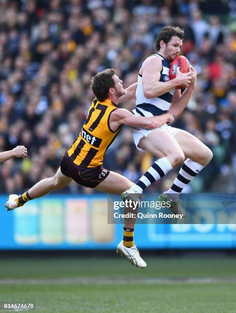 Patrick Dangerfield of the Cats marks over the top of Blake Hardwick of the Hawks during the round 17 AFL match between the Geelong Cats and the...