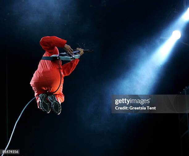 Tom Morello of the band Rage Against The Machine jumps into the air, dressed up as Guantanamo Bay prisoners, in orange jumpsuits and black hoods in...