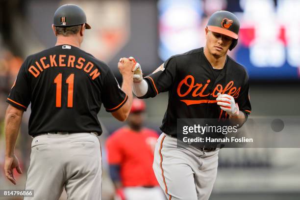 Third base coach Bobby Dickerson of the Baltimore Orioles congratulates Manny Machado on a home run against the Minnesota Twins during the game on...