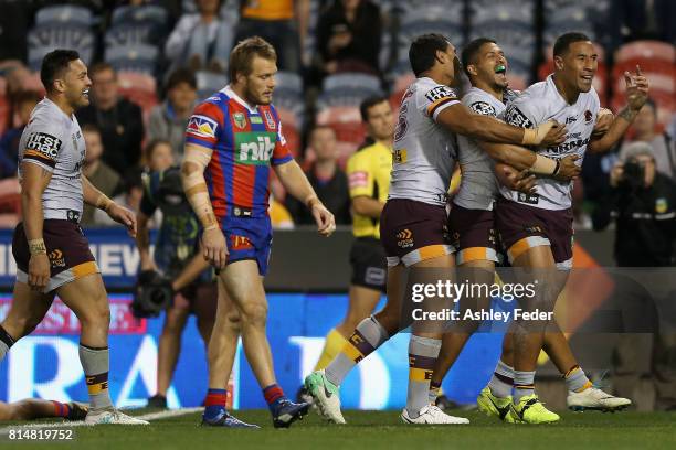 Tautau Moga of the Broncos celebrates his try with team mates during the round 19 NRL match between the Newcastle Knights and the Brisbane Broncos at...