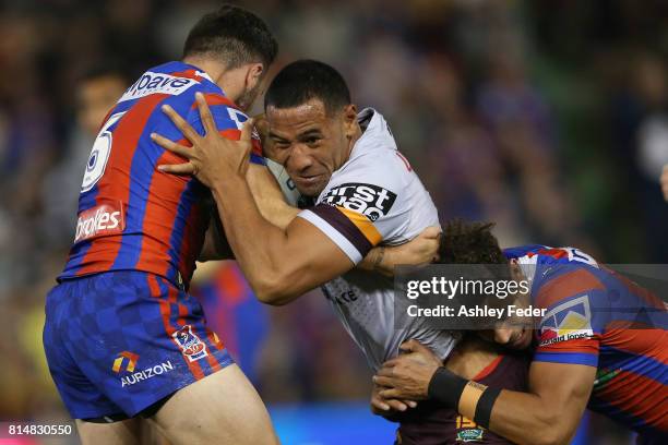 Tautau Moga of the Broncos is tackled by the Knights defence during the round 19 NRL match between the Newcastle Knights and the Brisbane Broncos at...