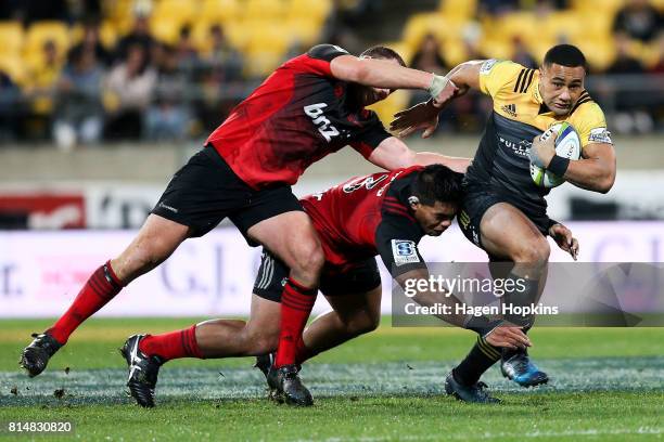 Ngani Laumape of the Hurricanes is tackled by Michael Alaalatoa and Wyatt Crockett of the Crusaders during the round 17 Super Rugby match between the...