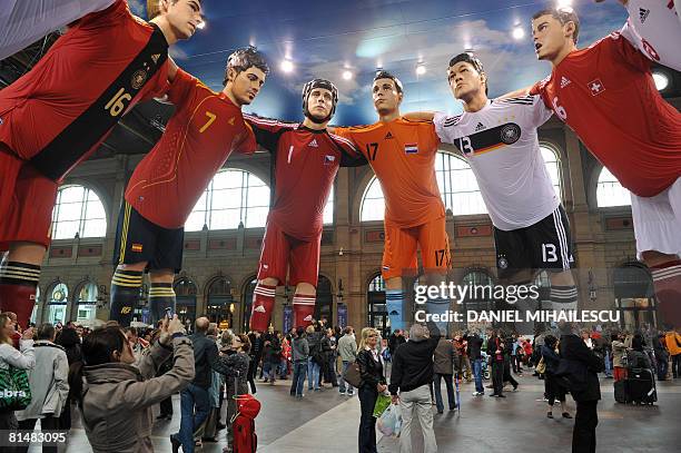 Pedestrians look at giant statues of players from different national football teams, Michael Ballack and Philipp Lahm from Germany, Karim Benzema and...