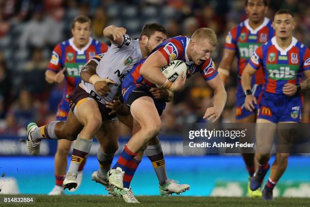 Mitch Barnett of the Knights is tackled by the Broncos defence during the round 19 NRL match between the Newcastle Knights and the Brisbane Broncos...
