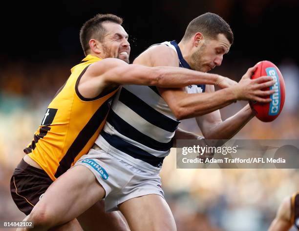 Luke Hodge of the Hawks playing his 300th game attempts to smother Sam Menegola of the Cats during the 2017 AFL round 17 match between the Geelong...