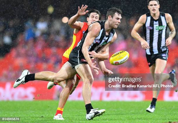 Matthew Scharenberg of the Collingwood Magpies is pressured by the defence during the round 17 AFL match between the Gold Coast Suns and the...