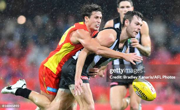 Matthew Scharenberg of the Collingwood Magpies is pressured by the defence during the round 17 AFL match between the Gold Coast Suns and the...