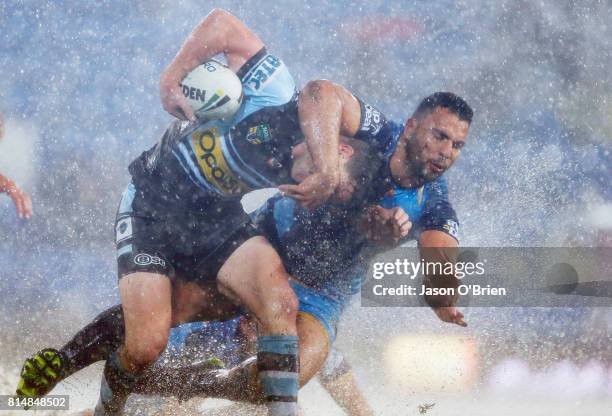 Chad Townsend of the sharks is tackled by Ryan James of the Titans during the round 19 NRL match between the Gold Coast Titans and the Cronulla...