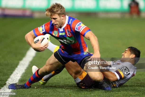 Brendan Elliot of the Knights is tackled by Anthony Milford of the Broncos during the round 19 NRL match between the Newcastle Knights and the...