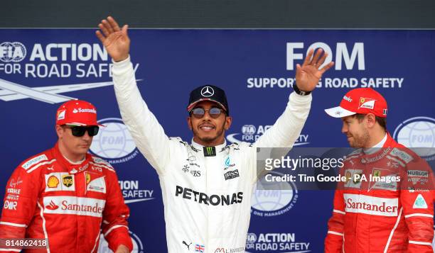 Mercedes' Lewis Hamilton celebrates on the podium after qualifying in pole position alongside second place Ferrari's Kimi Raikkonen and third place...