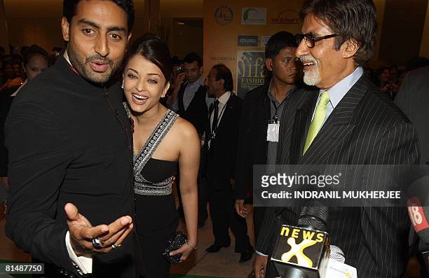Indian Bollywood actor Amitabh Bachchan laughs as son Abhishek Bachchan with his actor wife Aishwarya Rai Bachchan reacts to the media as they arrive...