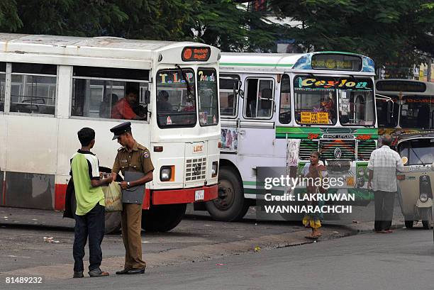 Sri Lankan policeman checks the bags of passengers at a bus stand in Maharagama suburb of Colombo on June 7, 2008. Sri Lankans are living on the edge...
