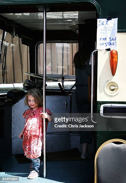 Girls swings on the pole of an old routemaster bus that has been converted into an art exhibition during the Vauxhall Art Car Boot fair in the Old...