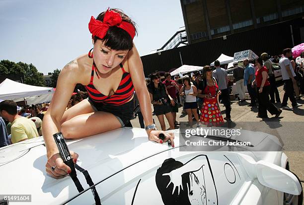 Illustrater and Aritist 'Miss Led' works on her artwork on the body of a Vauxhall car during the vauxhall Art Car Boot fair in the Old Truman Brewery...