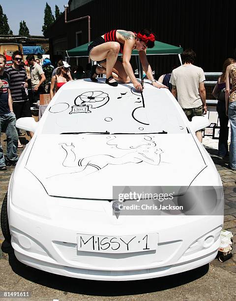 Illustrater and Aritist 'Miss Led' works on her artwork on the body of a Vauxhall car during the vauxhall Art Car Boot fair in the Old Truman Brewery...