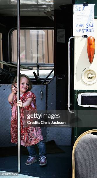 Girls swings on the pole of an old routemaster bus that has been converted into an art exhibition during the Vauxhall Art Car Boot fair in the Old...