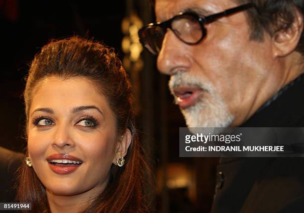 Indian actor Aishwarya Rai-Bachchan watches as father-in-law Amitabh Bachchan speaks to the media on arriving for the International Indian Film...