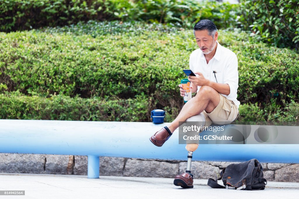 Japanese man holding his coffee as he uses an instant messaging application on his phone
