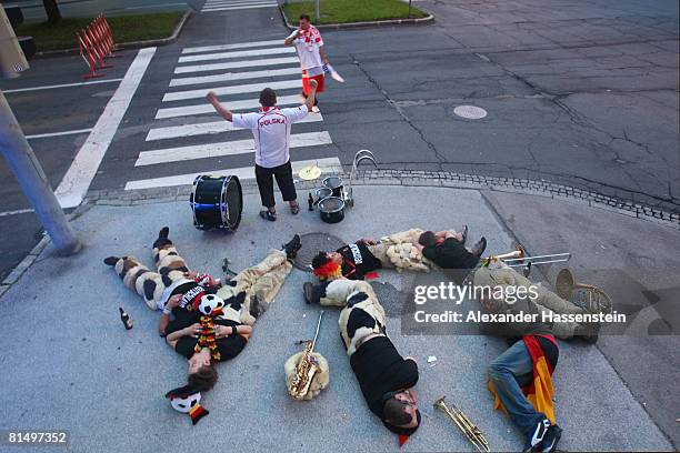 Polish football fans pose next to sleeping German football supporters on a street in downtown Klagenfurt on June 9, 2008 in Klagenfurt, Austria....
