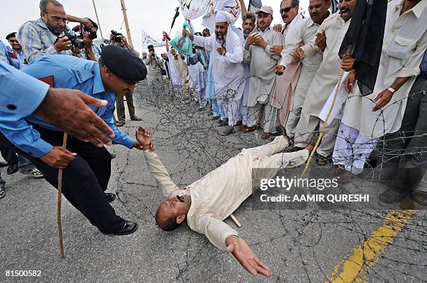 Pakistani policeman drags a government school teacher as they try to cross barbed wire during a demonstration in front of the Parliament House in...