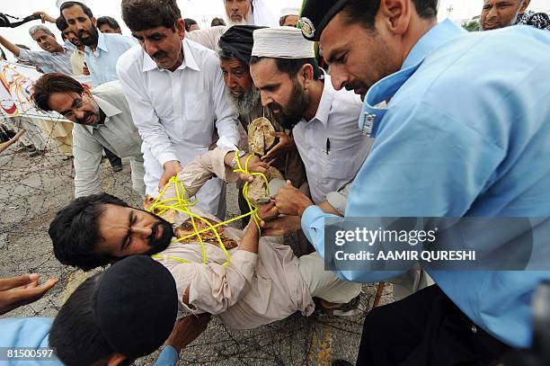 Pakistani policemen drag a government school teacher as they try to cross barbed wires during a demonstration in front of the Parliament House in...