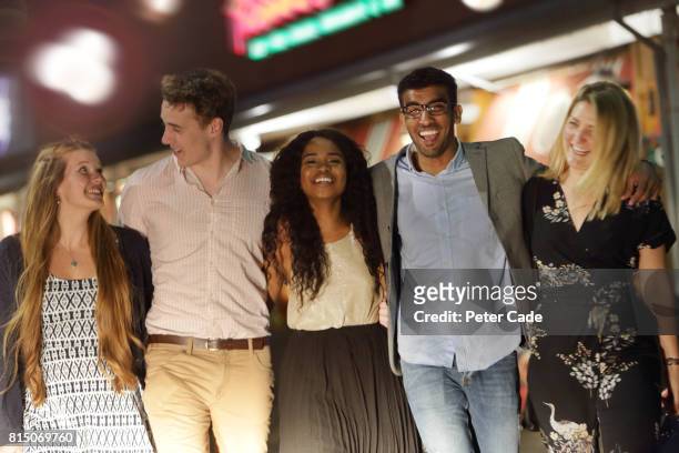 group of young adults walking outside of bars and restaurants at night - clique stock pictures, royalty-free photos & images