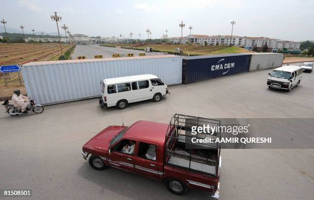 Pakistani motorists drive past containers that seal off a road leading to the Presidential Palace in Islamabad on June 10 ahead of the long march due...