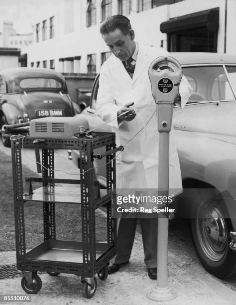 Technician Arthur Longley of Venner Ltd, using plug-in electronic time-testing equipment on a new parking meter at the company's factory in New...