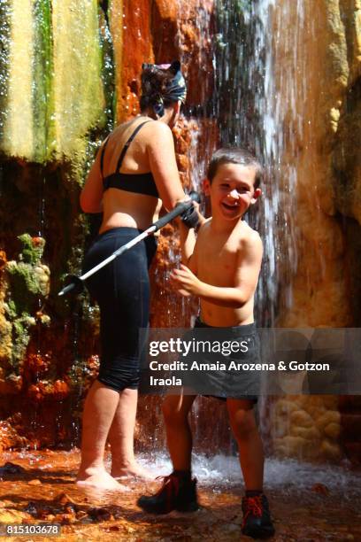 little boy and mother bathing in a colorful waterfall in caldera de taburiente national park on the island of la palma, canary islands. spain. - portrait lachen stock pictures, royalty-free photos & images