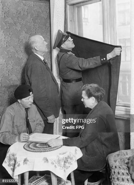 Air raid wardens helping a couple to black out their windows in preparation for an air raid blackout exercise in Berlin, scheduled for 19th March...