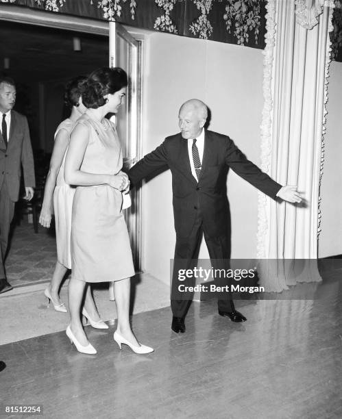 First Lady Jacqueline Kennedy , the wife of US President John F. Kennedy, is escorted out of the auditorium of the Biltmore Hotel by Felix Standen,...