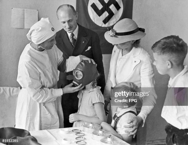 Nurse fitting a young girl with a government-issue gasmask, Germany, 4th September 1937.