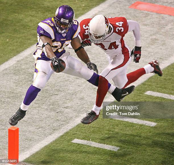 Chester Taylor attempts to hold the ball over the goal line while being pushed out by Robert Griffith during the game between the Arizona Cardinals...