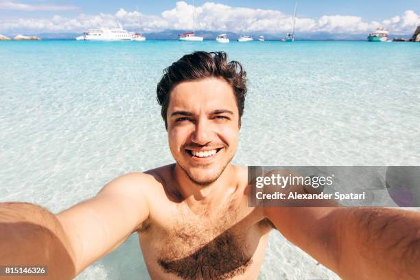 selfie of a young handsome man on the beach in greece - behaart stock-fotos und bilder