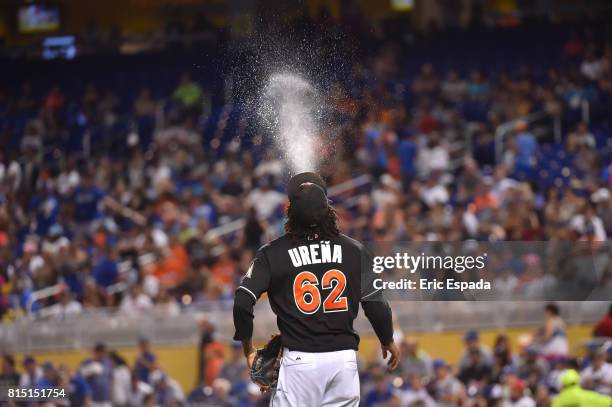 Jose Urena of the Miami Marlins spits water in the air on his way to the mound before the start of the third inning against the Los Angeles Dodgers...