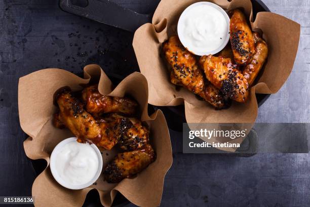 glazed spicy chicken wings with sesame seeds served in cast iron skillets - glazen pot stock pictures, royalty-free photos & images