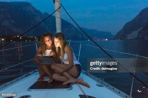 women using digital tablet on sailboat during blue hour - sailing ship night stock pictures, royalty-free photos & images