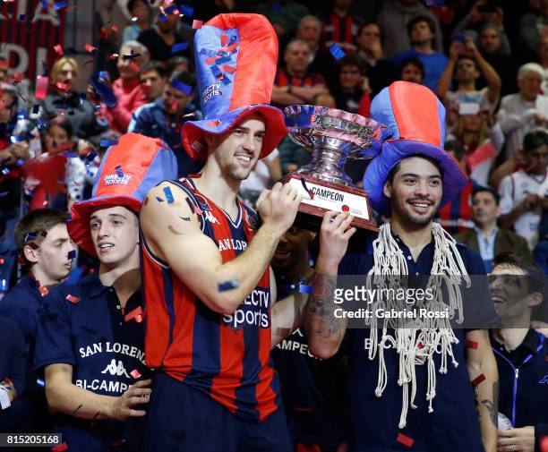 Marcos Mata and Nicolas Aguirre of San Lorenzo lift the trophy to celebrate after winning the fifth game between San Lorenzo and Regatas as part of...