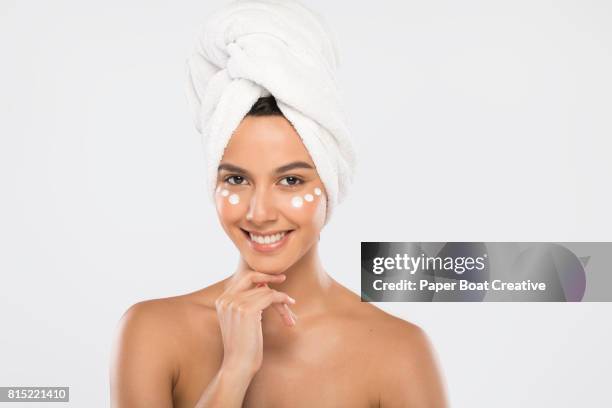 brown skinned girl wearing a towel around her head with moisturizer on her face - brown paper towel stock pictures, royalty-free photos & images