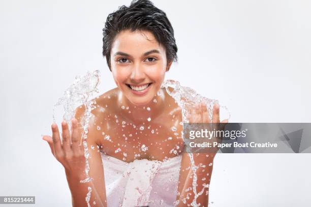 short haired and brown skinned girl splashing water to her face, wrapped in a white towel with white background - brown paper towel stock pictures, royalty-free photos & images
